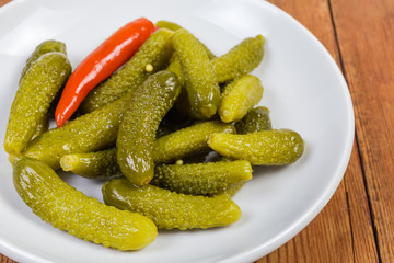 Pickled gherkins on white saucer, fragment close-up