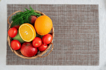 Vegetables and fruits in a basket on the table on a dark background top view