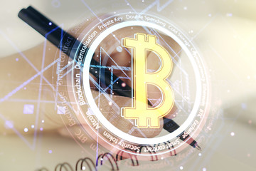 Double exposure of creative Bitcoin symbol with man hand writing in notebook on background. Cryptocurrency concept