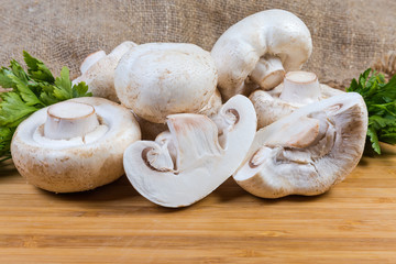 Fresh uncooked button mushrooms and parsley on the wooden surface