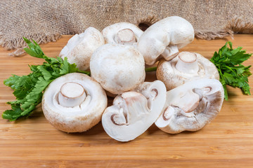 Fresh uncooked button mushrooms and parsley on the wooden surface