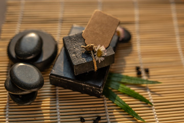 bar block of black carbon charcoal coal soap on a bamboo background with lava stones spa concept