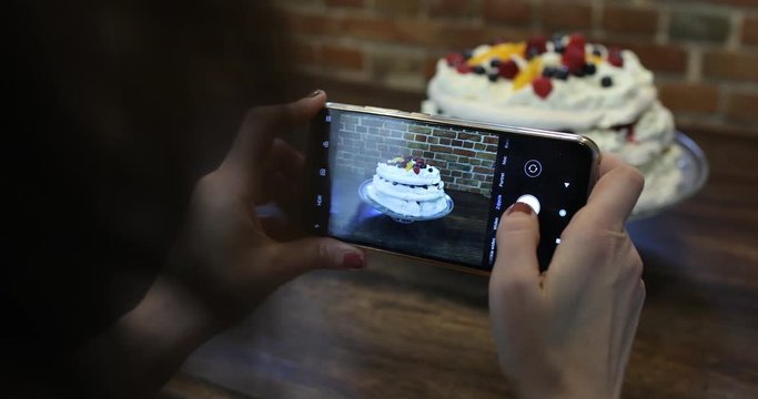 Pretty girl making photos and videos of her freshly cooked raspberry cake. Amateur cooking, homemade pastry and social media sharing concept. 4K steadicam shot