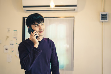 Handsome young man talking on the mobile phone in the house.