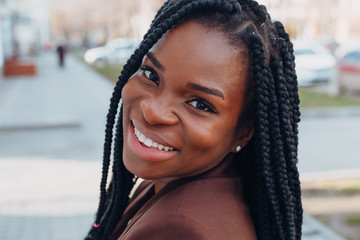 Close up portrait of a beautiful young african american woman with pigtails hairstyle in a brown...