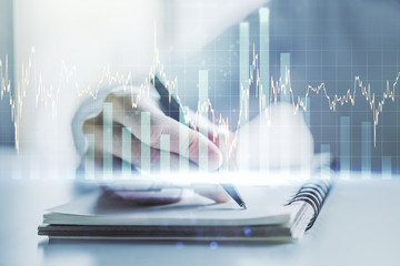 Multi exposure of abstract financial graph with hand writing in notebook on background, financial and trading concept