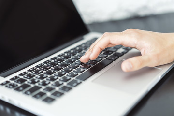 Businessman typing on laptop keyboard in sunny office, business and technology concept. Close up