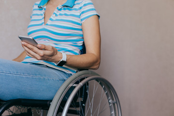 close up of a young woman in a wheelchair with a mobile phone in her hands at home. Recovery and...