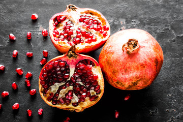 ripe pomegranate, slice and seeds on a black background