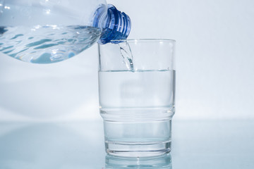Mineralwasser aus Plastikflasche in das Glas giessen