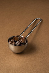 Measuring spoon filled with coffee on a brown surface. Close-up.