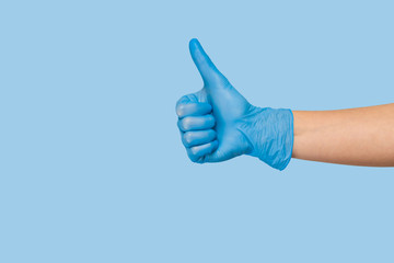 Doctor's hand in blue medical glove showing ok sign on a blue background. infection control