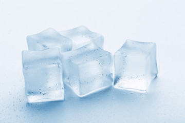 several melted ice cubes with drops on a light background with blue tinting