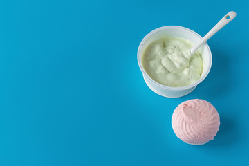 Yogurt in a glass on a blue background with marshmallows. A wholesome light diet breakfast. Dairy products..