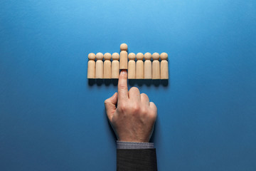 Hand of businessman chooses best candidate among figures of hired people. Recruiter and headhunter concept. Best employer resource.