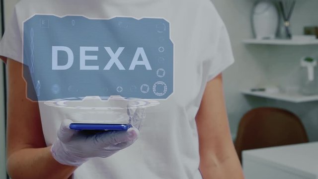 Doctor in medical glove against background of doctor's office with HUD hologram text Dexa. Hand holds futuristic holographic gadget. Medical technology concept of the future