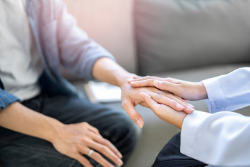 close up of doctor and patient holding hand, female doctor hands coupling the patients hand in comfort on bad news of relatives or positive testing on illness and diseases in hospital or clinic office