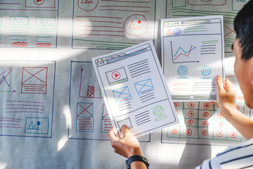 close up male asian ui/ux designers working and designing a user interface for website and...