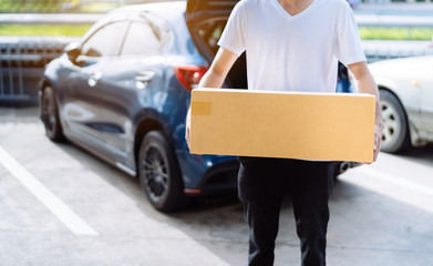 Delivery man carrying cardboard box for sending to receiver customer by transportation system hatchback car, Business product service for convenience of customer while the person is working at home.