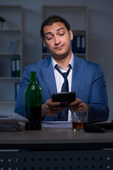 Alcohol addicted businessman working late in the office