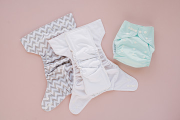 Reusable cloth baby diapers. Eco friendly cloth nappies on a pink background. Sustainable...