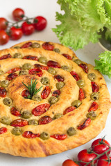 Homemade italian flat bread Focaccia contorta. With olives, olive oil, rosemary, tomatoes. Traditional recipe. Vegan. White concrete texture background.