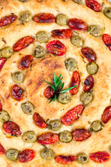 Homemade italian flat bread - Focaccia contorta. With olives, olive oil, rosemary, tomatoes. Traditional recipe. Vegan. White concrete texture background.
