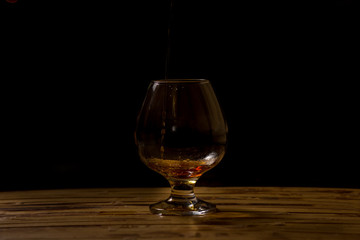 Liquid, alcohol of caramel color close up. A glass transparent with patches of light. Indoors. Horizontal format. Color. Photo.