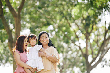 Fototapeta premium Happy three generations of women spending summer day in city park