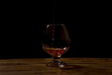 Shot glass with alcohol on a black background. The isolated object on a black background. Material...