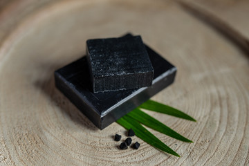 charcoal coal carbon black soap bar on a raw wood background lava stone spa skin care hygiene concept 
