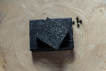 charcoal coal carbon black soap bar on a raw wood background lava stone spa skin care hygiene concept 