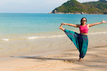 Asian Thai woman practicing yoga in Ao Thong Nai Pan Noi beach, Koh Phangan island, Thailand
