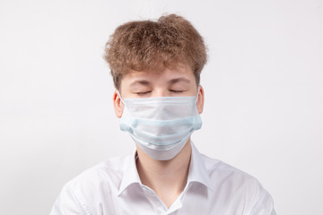 Teenager boy with eyes closed in protective medical mask to protect against the virus and coronavirus