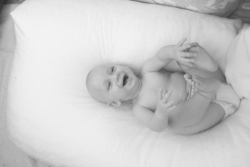 a newborn baby is lying in bed, smiling and playing with a toy