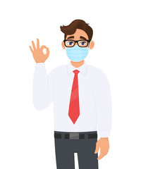 Young business man wearing face medical mask and showing okay, OK sign. Trendy person covering surgical mask and gesturing agree, success symbol with fingers. Cartoon design illustration in vector.