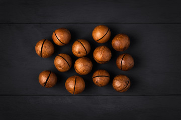 Macadamia nuts on a dark wooden background in the center