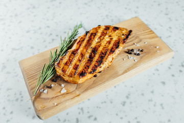 Grilled chicken fillet steak on wooden plank