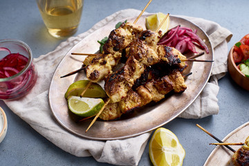Chicken tikka kebab with marinated onion, fresh salad and yoghurt sauce. Traditional indian cuisine, delicious starter. Creative flatlay