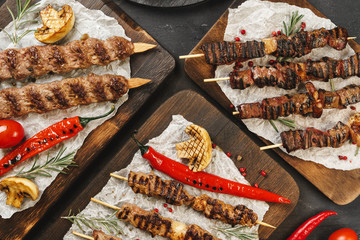 Grilled Lula kebab on skewers served on wooden board, black table background