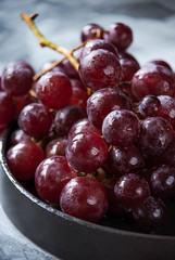 wet bunch of fresh purple grapes on dark plate