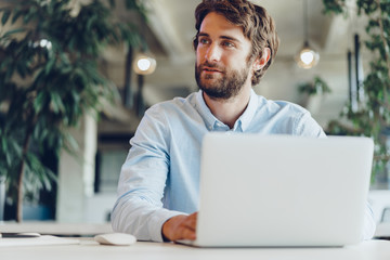 Businessman in shirt working on his laptop in an office. Open space office