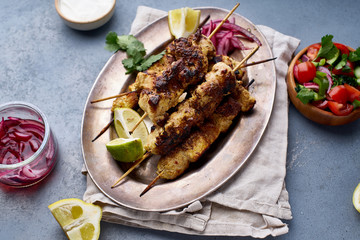 Chicken tikka kebab with marinated onion, fresh salad and yoghurt sauce. Traditional indian cuisine, delicious starter. Creative flatlay