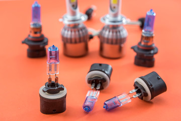 Different shapes and sizes car light bulbs isolated on orange. Modern auto glass lamp