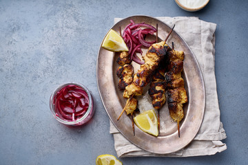 Chicken tikka kebab with marinated onion, fresh salad and yoghurt sauce. Traditional indian cuisine, delicious starter. Creative flatlay. Overhead image with text space