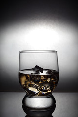 a glass of whiskey with ice is on the table, vignetting