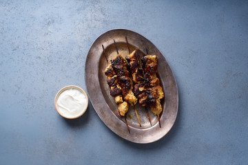 Chicken tikka kebab with marinated onion, fresh salad and yoghurt sauce. Traditional indian cuisine, delicious starter. Creative flatlay. Overhead image with text space