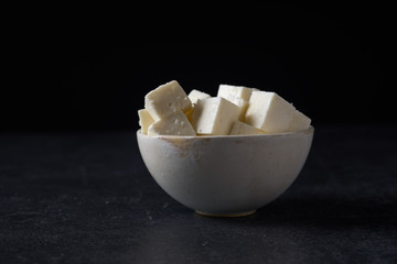 Traditional indian cheese paneer. Vegetarian homemade soft cheese in cheesecloth on dark background.