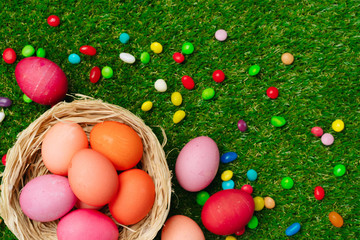 Fototapeta na wymiar Colored eggs and vibrant candies on grass. Easter composition