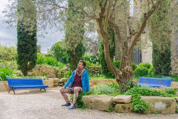 Naklejka na ściany i meble Gorgeous man sitting on bench outdoors in a park
